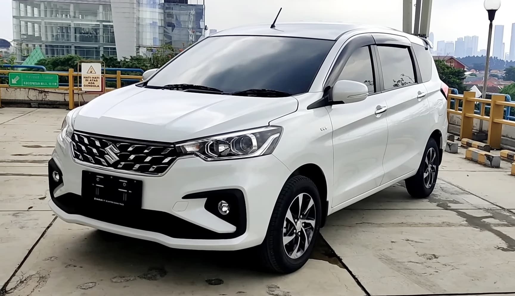 White Suzuki Ertiga parked on a rooftop with city buildings visible in the background.