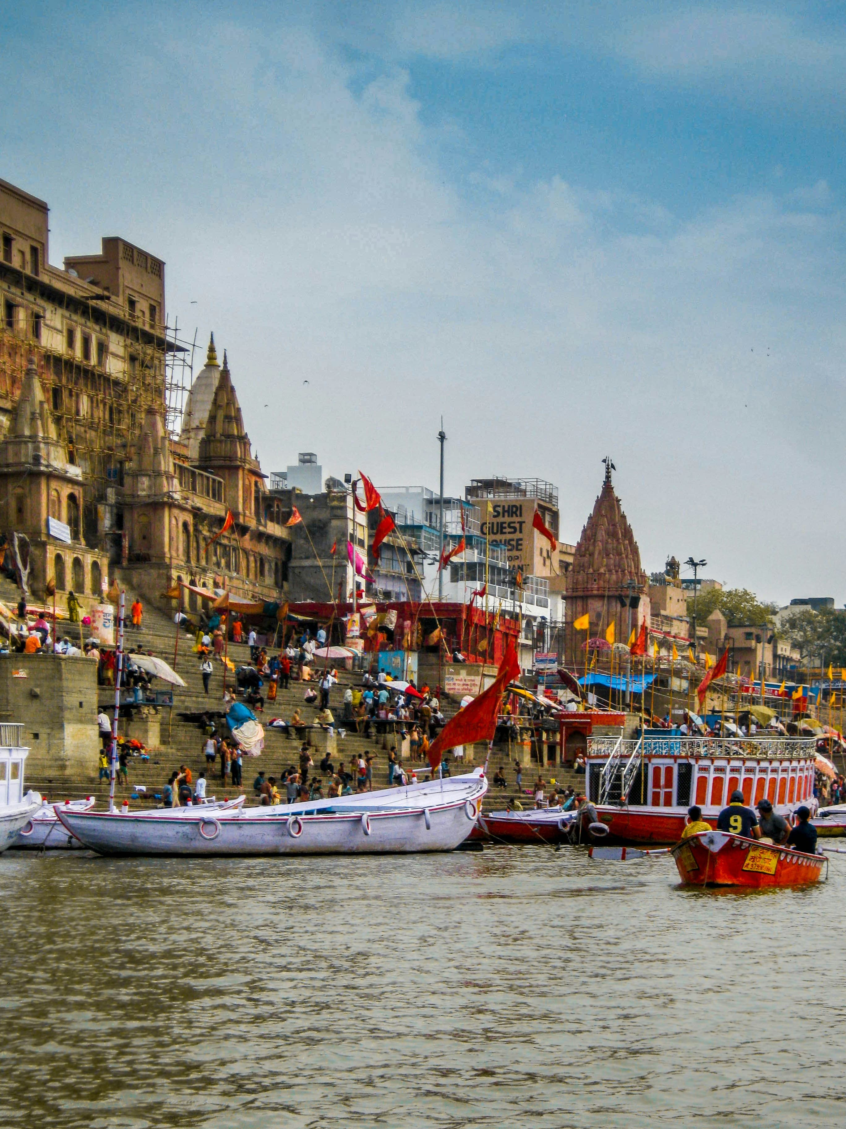 Boats on the Ganges river near the bustling ghats and ancient temples of Varanasi, India.