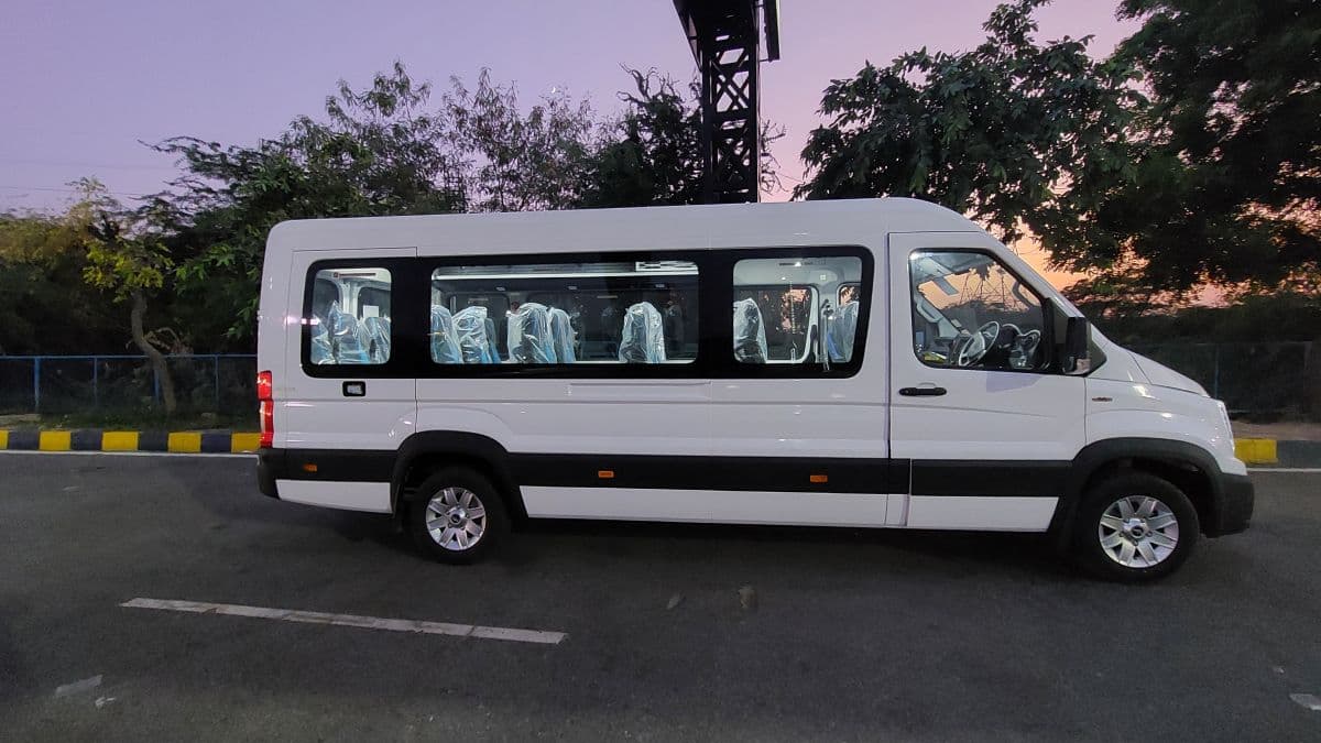 White passenger van with plastic-covered seats parked on a road against a twilight sky.